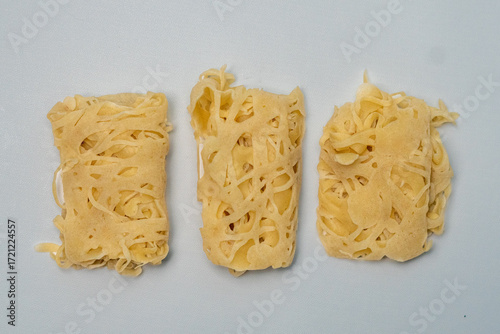 Three tempting pieces of roti jala are neatly presented. Their delicate net-like patterns showcase the beauty of Malay tradition, ready to indulge the senses with their soft texture and flavor.