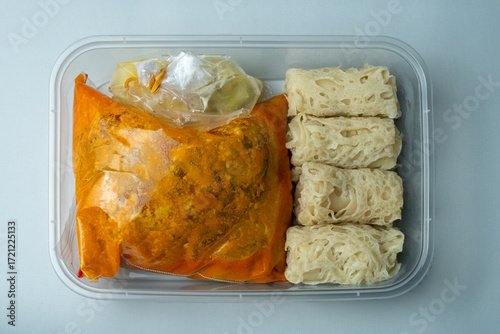 Golden roti jala served with rich curry sauce in a plastic pack and fresh colorful pickles. This traditional Malay dish looks delicious, perfect for illustrating authentic food content.