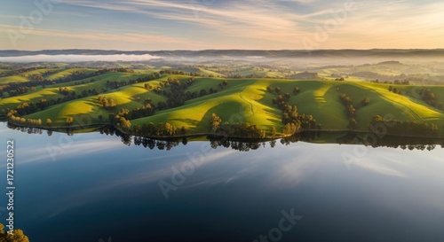 Sunrise over rolling hills and calm lake Aerial landscape photography