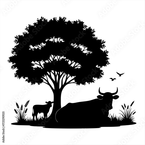 Silhouette of a cow and calf resting under a large tree with birds flying in the background
