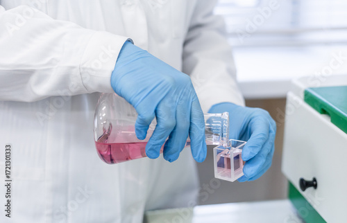 A woman in a medical laboratory performs a chemical test by placing a cuvette with liquid into a spectrophotometer to subsequently determine the concentration of the solution