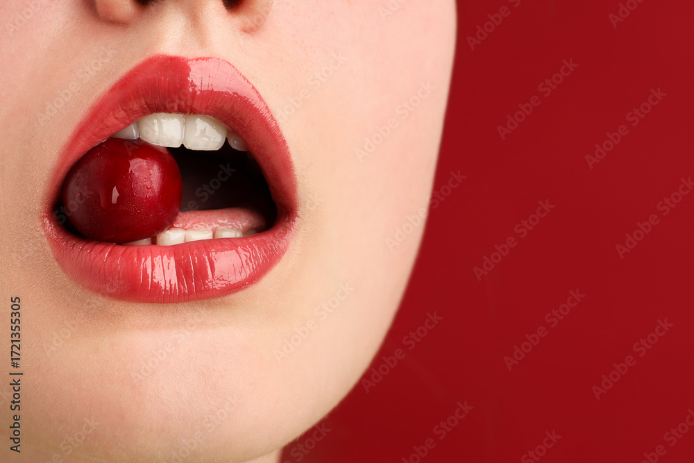 Obraz premium Woman with beautiful lips makeup and cherry on red background, closeup. Space for text