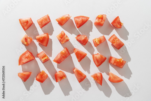Rows of red tomato chunks on white background. Top view