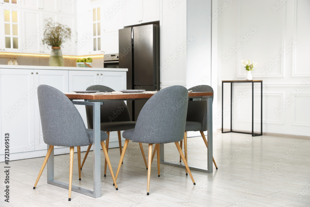Fototapeta premium Kitchen interior with dining table, place setting and grey chairs