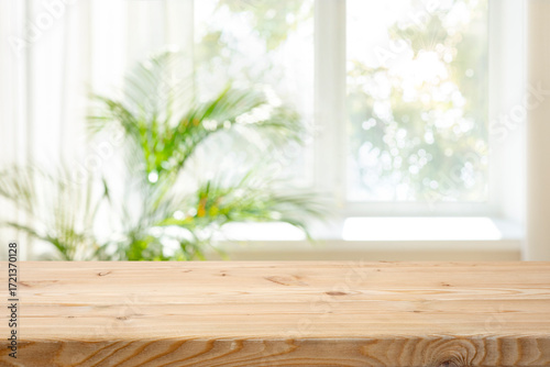 Empty wood table top on blurred curtained window and abstract greenery from garden background