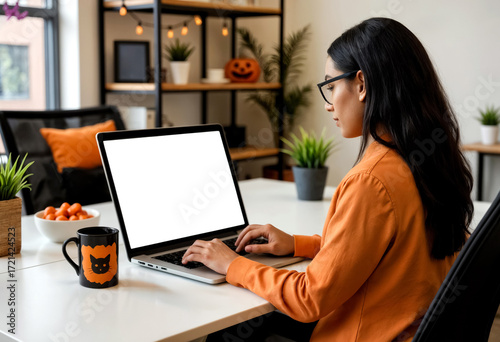young woman working on laptop in room decorated for halloween, monitor mockup, side view
