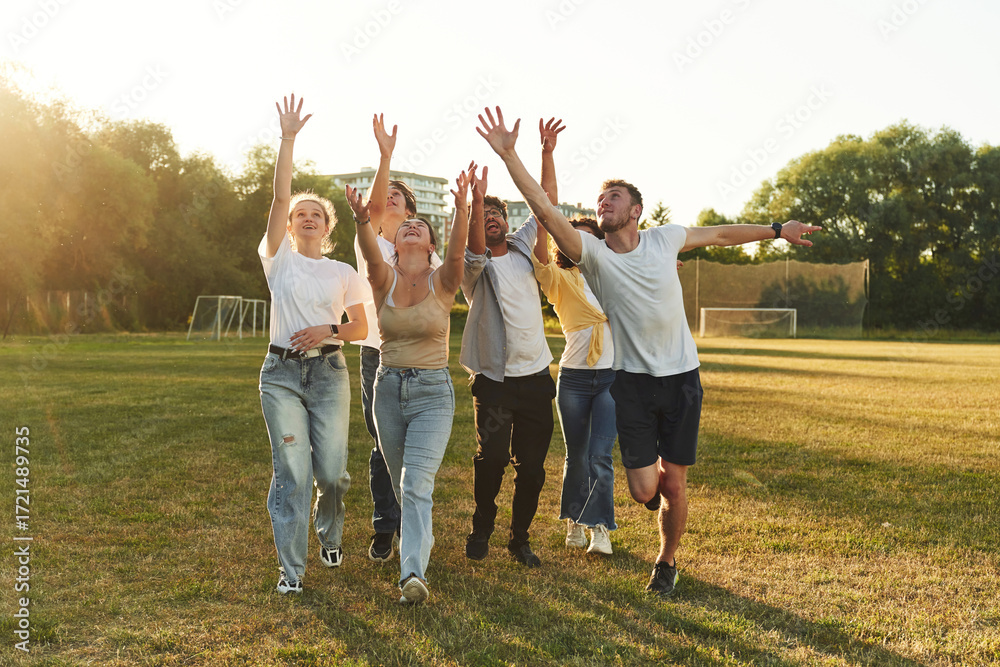 Obraz premium Arms high up, trying to catch something with hands. Young friends are having fun on the field