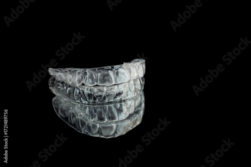Transparent invisalign retainers brackets pattern on black background. Dental invisible orthodontic care