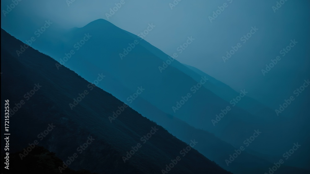 Fototapeta premium A peaceful wilderness scene at dusk, with a mountain range silhouetted against a sky of deep twilight blue.