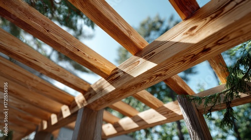Detailed view of intersecting wooden beams of a pergola, with natural light and tree branches in the background.