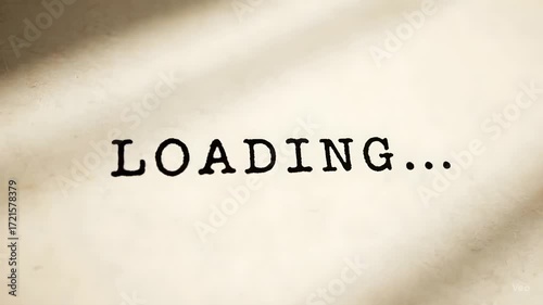 Conceptual image of waiting and progress featuring the word LOADING... in a vintage typewriter font on textured beige paper