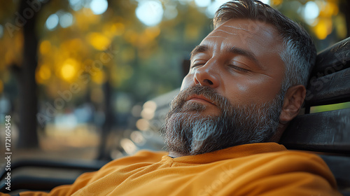 A man relaxes on a park bench, enjoying the tranquility of nature and the warmth of the sun during a peaceful afternoon.