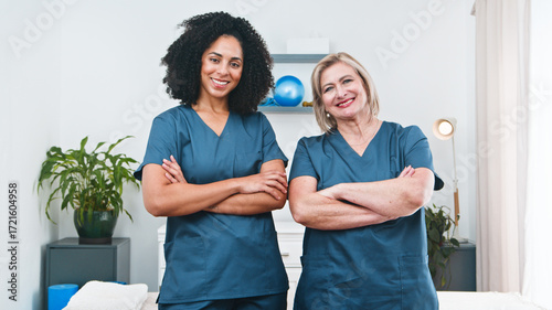 Two Female Physiotherapists Stand Confidently With Crossed Arms In A Clinical Therapy Setting