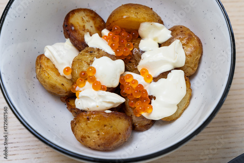 A bowl of roast potato with creme fraiche and salmon roe.