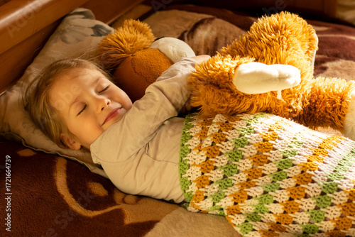 Quadro su tela smiling little girl with closed eyes hugging her teddy bear toy slepping on the