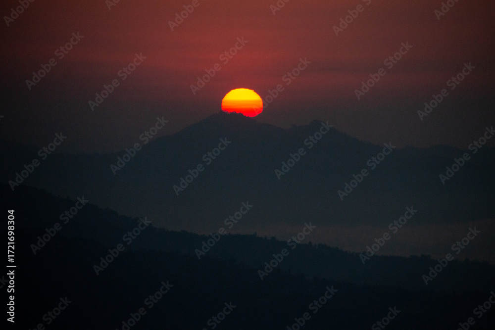 Obraz premium Fiery Sunset Over Mountain Silhouette