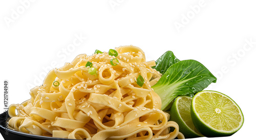 Delicious fettuccine pasta with sesame seeds garnished with fresh green lime and leafy greens on black plate, perfect for food menus and culinary presentations