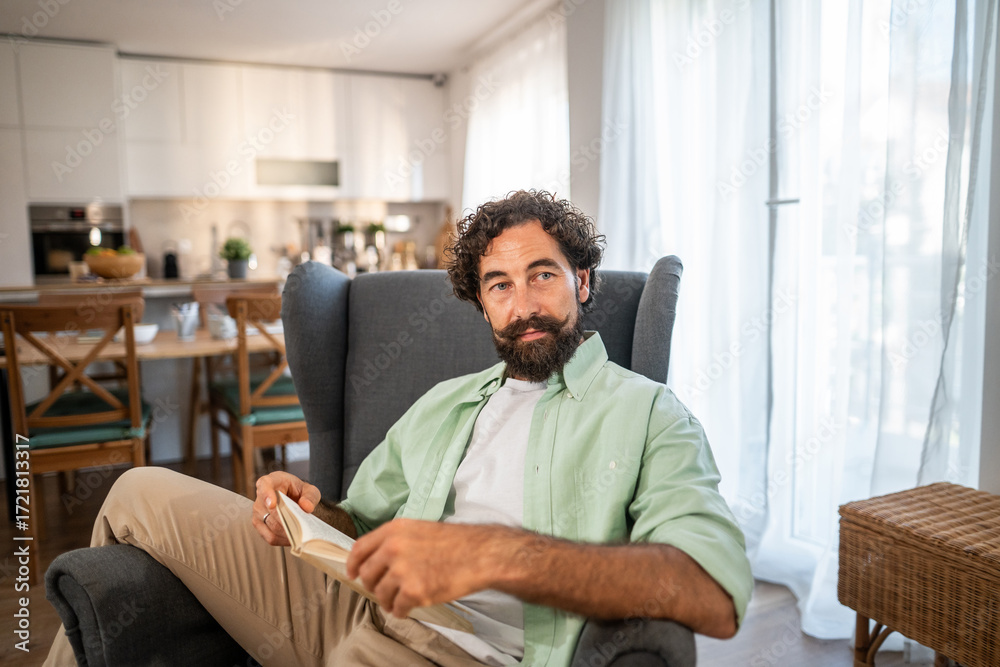 Fototapeta premium Man resting in armchair, reading and unwinding at home