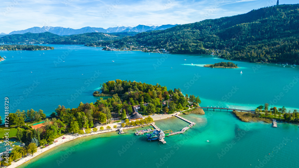 Naklejka premium Aerial view of Portschach am Worthersee, Austria, with turquoise lake waters, boats, piers and alpine scenery. Popular summer holiday destination for relaxation, wellness and tourism