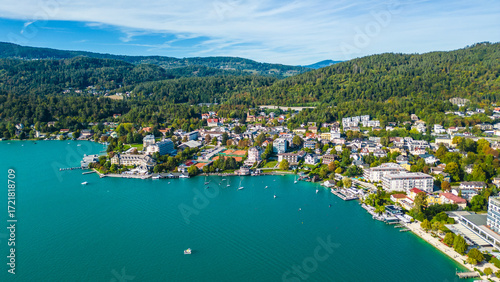 Aerial view of Portschach am Worthersee, Austria, with turquoise lake waters, boats, piers and alpine scenery. Popular summer holiday destination for relaxation, wellness and tourism