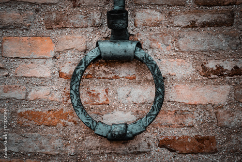 Ancient wrought iron ring for tying animals, horses, mules or cattle with rope, on a stone wall
