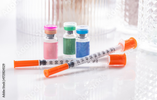 Close up of Vials with Various Injectable Compounds Next to Syringes