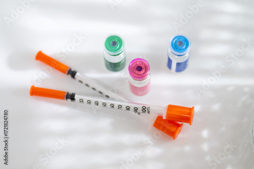 Close up of Vials with Various Injectable Compounds Next to Syringes