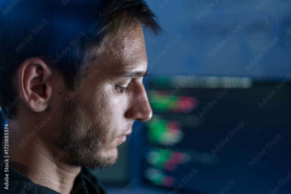 Fototapeta premium Caucasian male programmer coding late night in dark room.