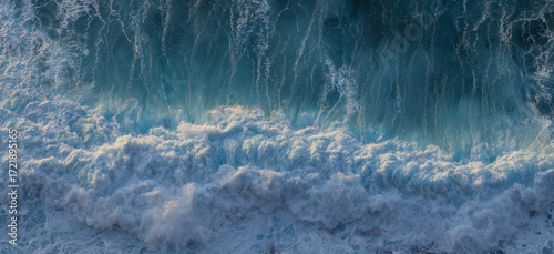 Big ocean wave breaking on the beach at sunset. White seagull soaring over the wave. Atlantic ocean in Nazare, Portugal. 