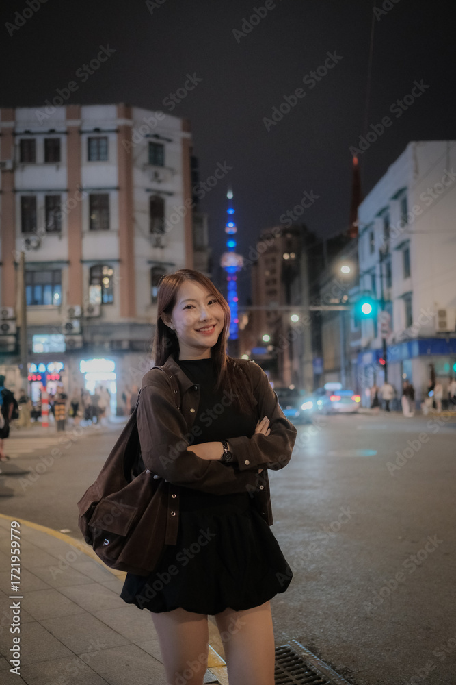 Fototapeta premium A woman is standing on a city street, wearing a black jacket and black skirt. traveller tourist concept.