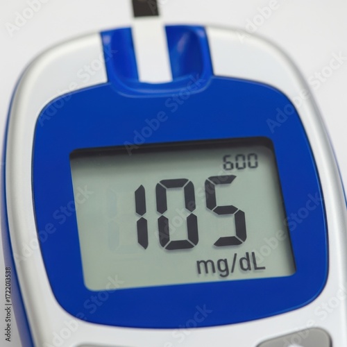 Close-up of a digital glucose meter displaying a blood sugar reading of 105 mg/dl
