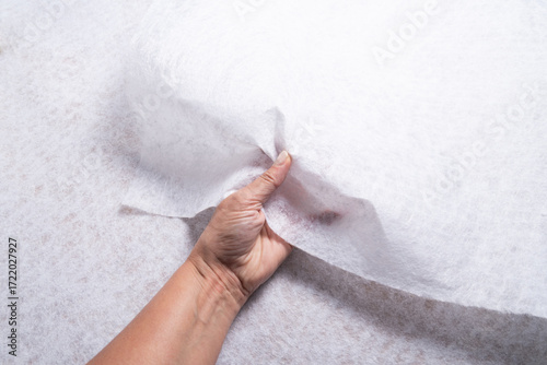Hand Holding White Geotextile Fabric Sheet with Visible Texture, Close-Up