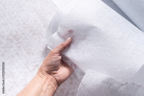 Hand Holding White Geotextile Fabric Sheet with Visible Texture, Close-Up