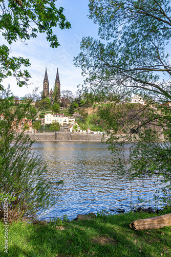 View of the Church of St. Peter and St. Paul at Vysehrad, Prague, Czech Republic. Historic neo-Gothic landmark surrounded by greenery under a clear sky.