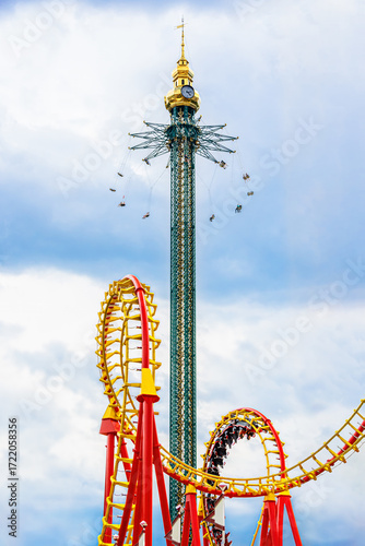 Amusement park rides in Prater Vienna summer, towering swing carousel and looping roller coaster creating thrilling skyline attraction.
