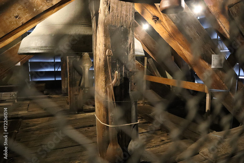 Bild auf Leinwand Estructura de madera en torre con grandes campanas metálicas, luz filtrada y vista protegida por malla