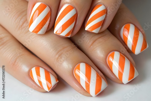 Orange and white striped nail art design featuring alternating bold stripes on a manicured nail surface.