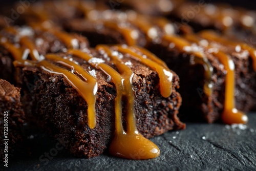 Rich Fudgy Brownies Drizzled with Golden Caramel Sauce and Sea Salt Flakes on Dark Surface