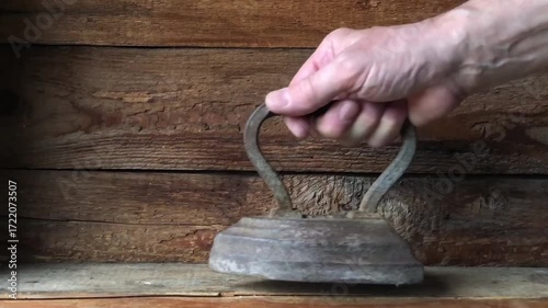 A man places an antique cast iron iron on a wooden shelf