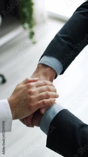 Diverse professional hands, varied skin tones & sleeve styles, stack quickly in a bright office with bokeh, showcasing trust, synergy. Concept of shared success and collaboration