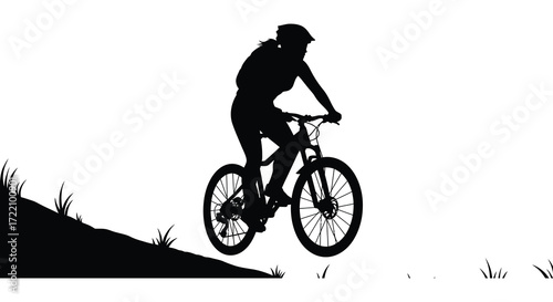 Silhouette of a mountain biker ascending a hill against a bright background
