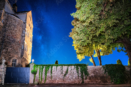 Schloss Seeburg in der Nacht mit daneben liegender Milchstraße und einem Baum