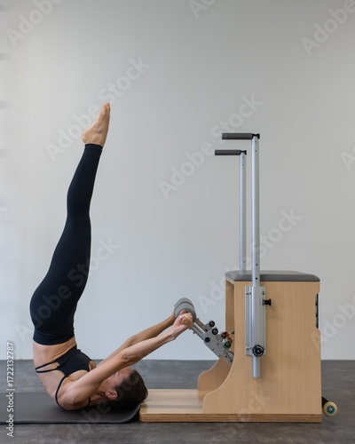 Caucasian woman doing Pilates on classic chair.