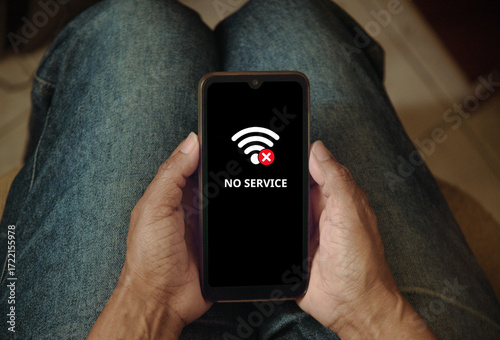 Cell phone showing: No service on the screen. Woman searching for mobile coverage on the mobile phone, no service screen.