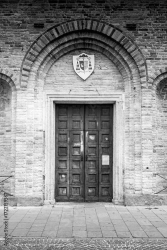 Historic Wooden Door with Arched Brick Frame and Heraldic Emblem