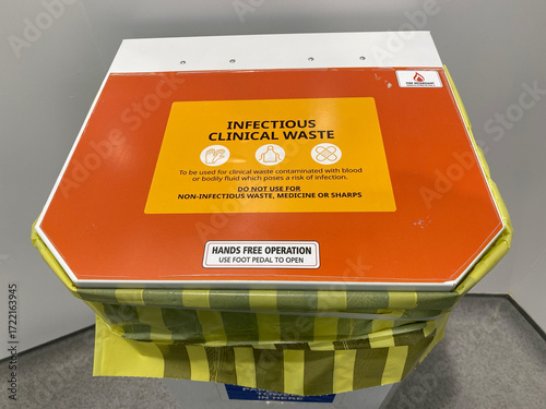 Hands free clinical waste bin with orange lid—biohazard disposal, hygiene protocol, and infection control.