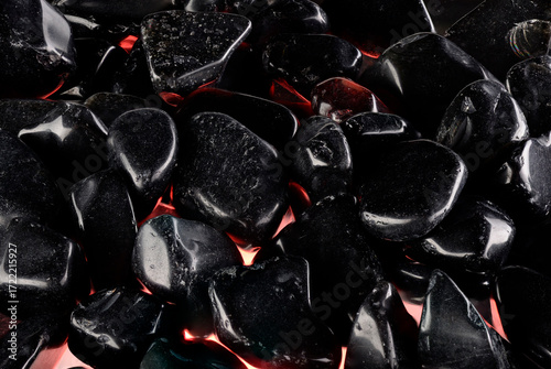 Black polished stones texture background and red light