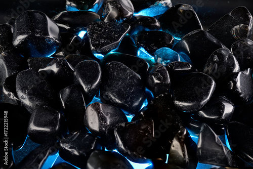 Black polished stones texture background and blue light