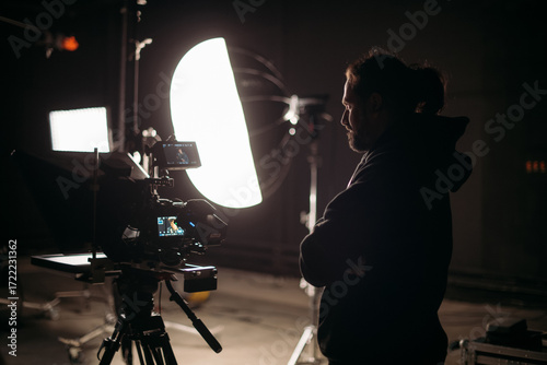 The director of photography with a camera on the set. A professional videographer is working on filming a movie or commercial for a TV series. The filming process takes place indoors in a studio.