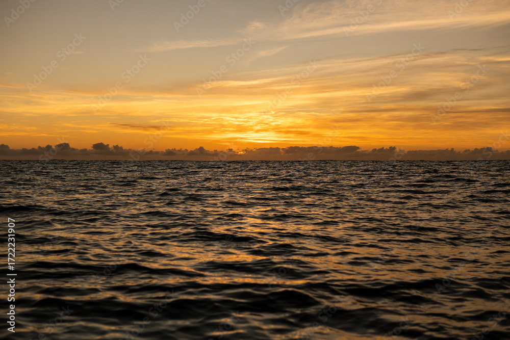 Obraz premium Golden sunrise in Itacaré, Bahia, Brazil. Boats floating on calm sea, yellow light on the horizon, tropical coastal landscape with warm tones and natural beauty.